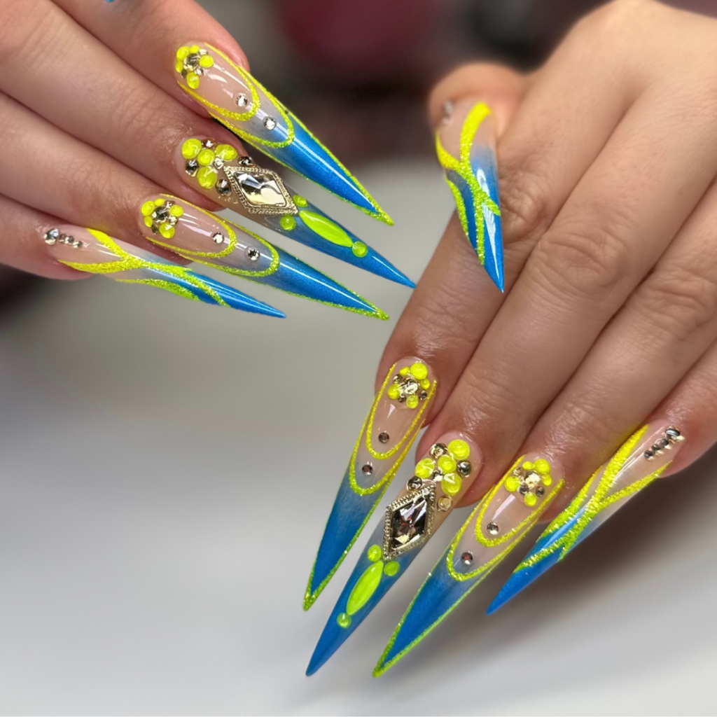 Close-up of long nails featuring creative freestyle nail designs with intricate patterns, vibrant colors, and decorative accents in a professional nail salon setting