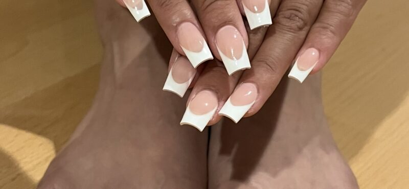 Close-up of elegant French tip nails paired with a smooth, vibrant single color pedicure, showcasing a polished and sophisticated look