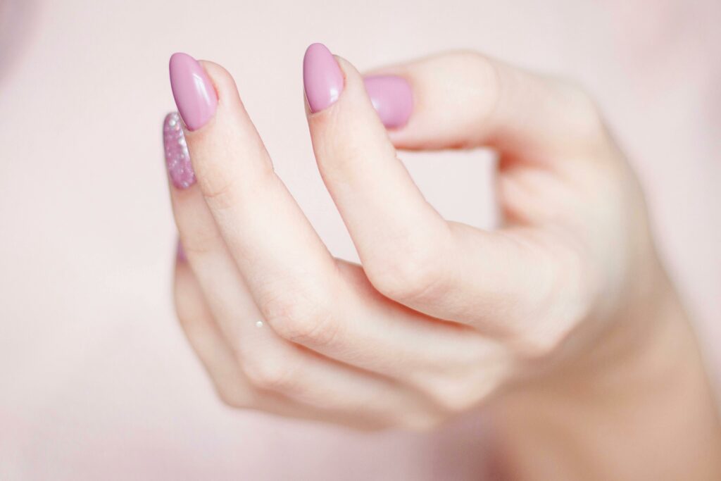 Glamorous pink hybrid gel nails with sparkling glitter accents for a dazzling look