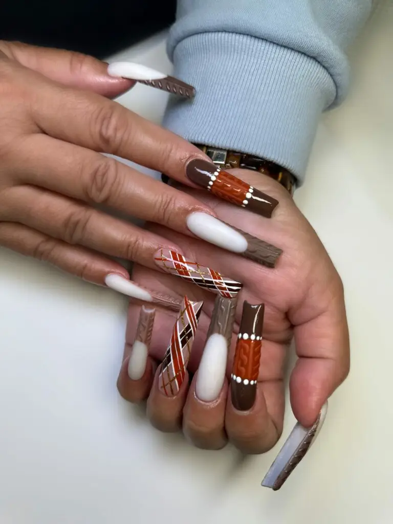 Close-up of fall-inspired nails featuring sweater texture and plaid designs in warm tones of brown, orange, and cream. Created at NAB Nail Bar, Las Vegas.