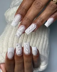 Cozy white sweater nails with delicate snowflakes, perfect for winter holiday nail art.