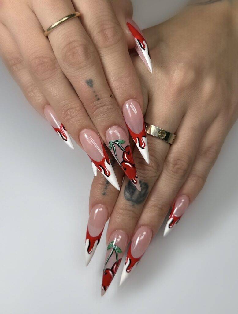 Bold stiletto-shaped Valentine’s Day nails featuring cute cherry designs, perfect for a playful and romantic look in Las Vegas.