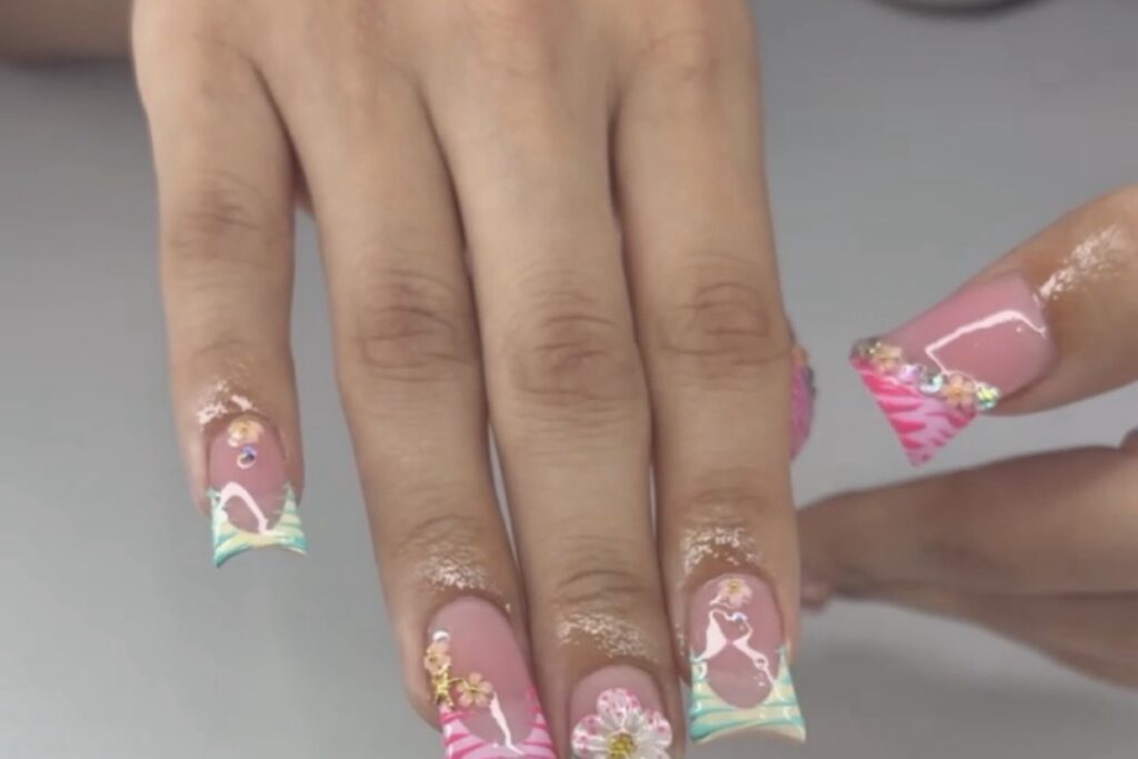 Freestyle duck nails with hand painted floral art glitter and pastel tips using the extra width of the flared shape as a canvas nab nail bar | nails lashes and beauty in las vegas