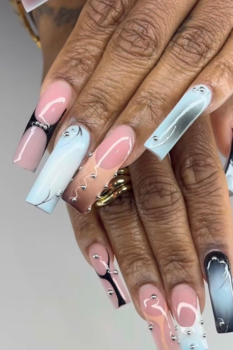 Long coffin Gel X nails in pink and baby-blue ombré with white swirls and silver studs, done at NAB Nail Bar in Las Vegas
