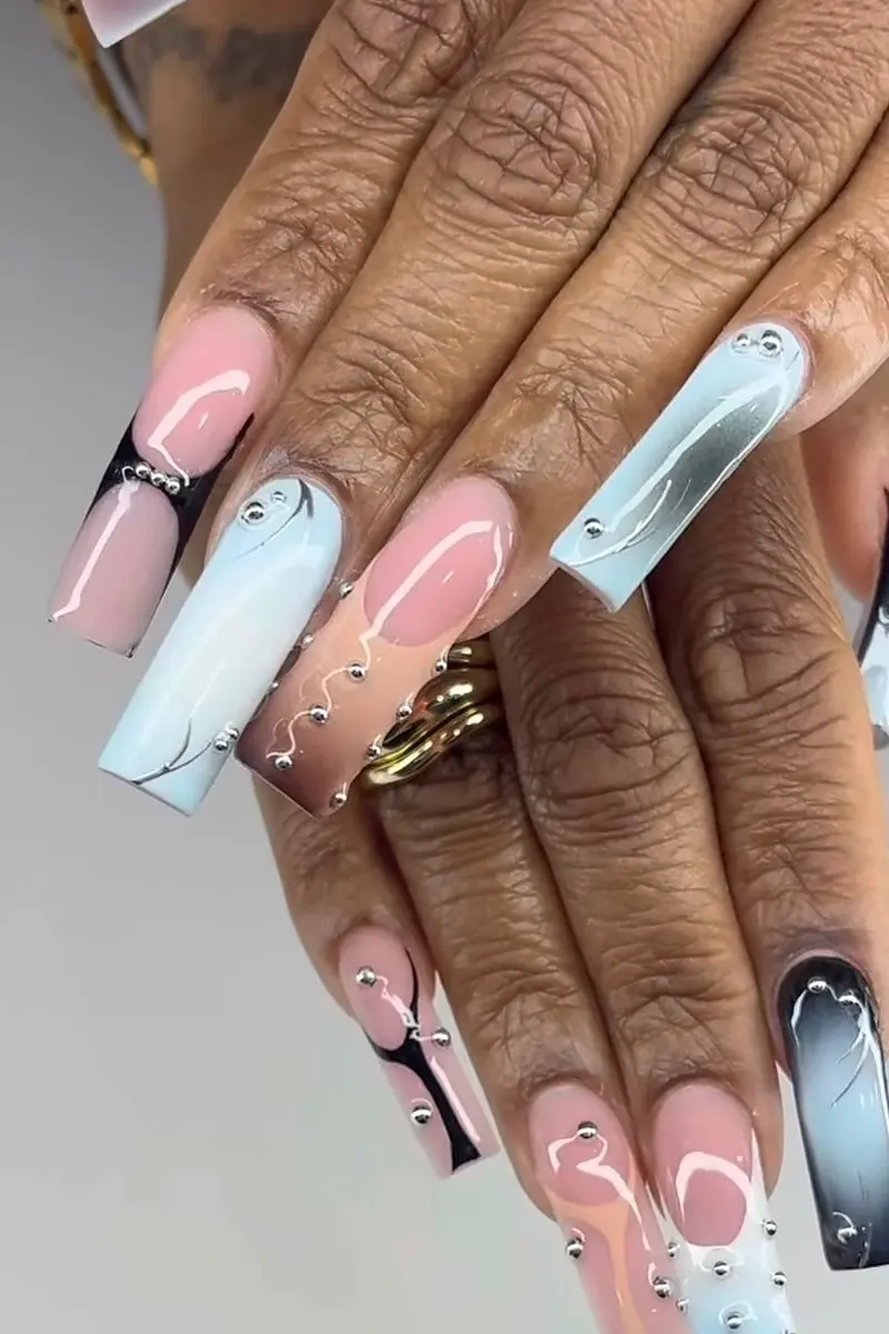Long coffin Gel X nails in pink and baby-blue ombré with white swirls and silver studs, done at NAB Nail Bar in Las Vegas