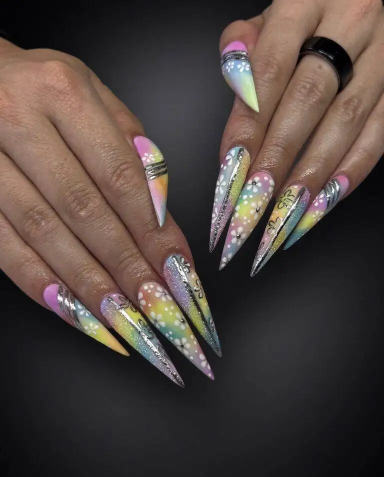Long stiletto nails with pastel rainbow gradient, white flower accents, and metallic silver stripes.