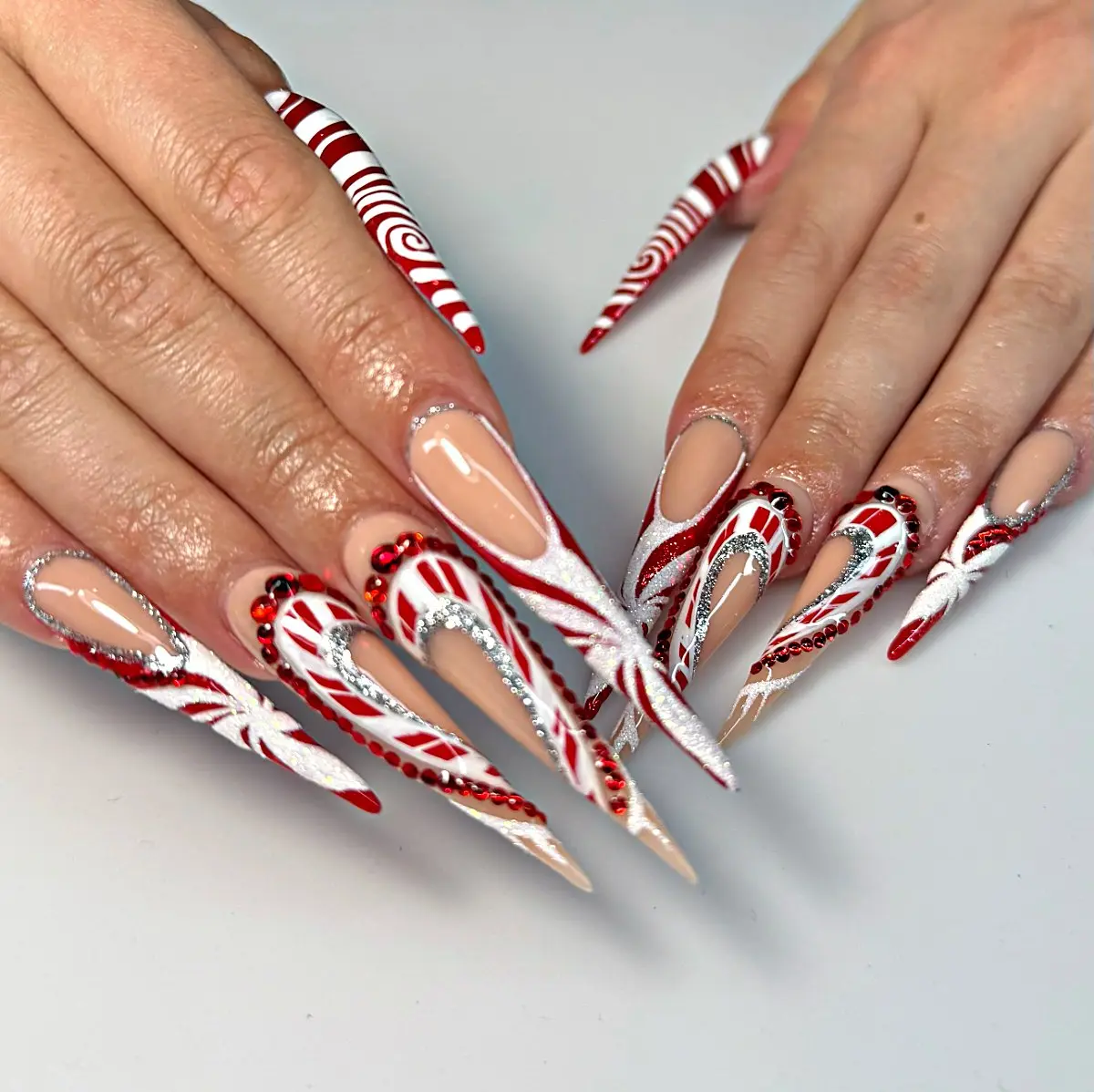 Candy cane and peppermint swirl christmas stiletto nails with red rhinestones at nab nail bar las vegas nab nail bar