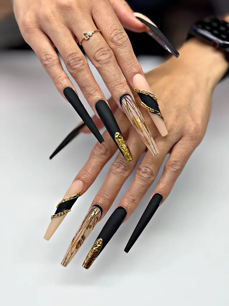 Extra long coffin Gel X nails in matte black and nude with gold foil and gold chains at NAB Nail Bar in Las Vegas