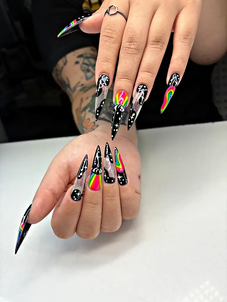 Extra long stiletto Gel X nails in black with rainbow swirls, stars and glitter at NAB Nail Bar in Las Vegas