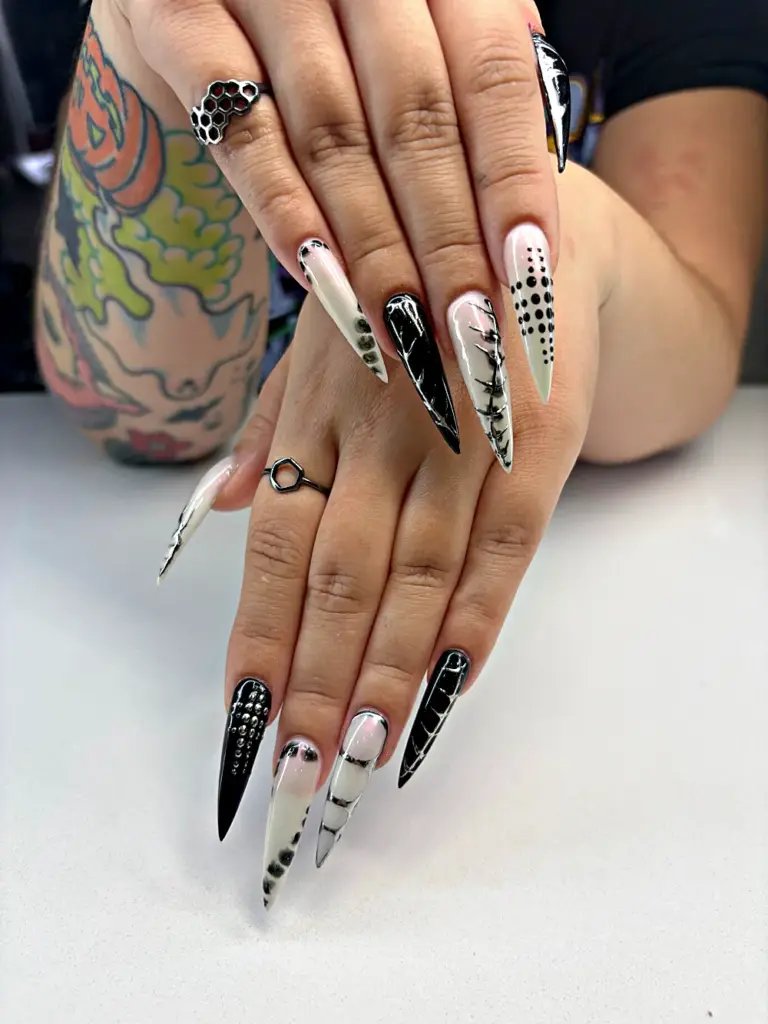 Extra long stiletto Gel X nails in black and white with silver chrome lines and studs at NAB Nail Bar in Las Vegas