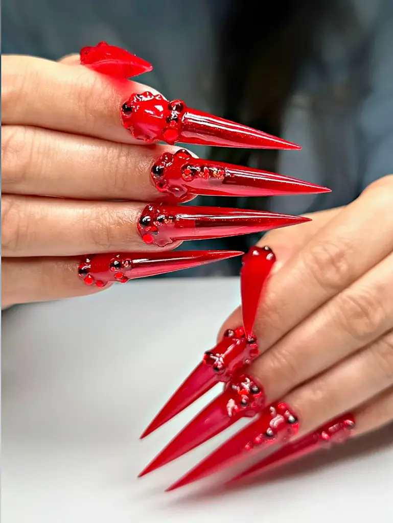Extra long stiletto Gel X nails in red jelly with red rhinestones at NAB Nail Bar in Las Vegas