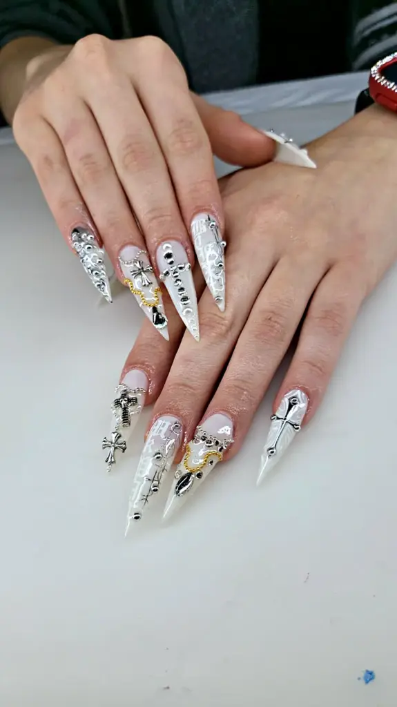 Extra long stiletto Gel X nails in milky white with silver crosses, chains and studs at NAB Nail Bar in Las Vegas