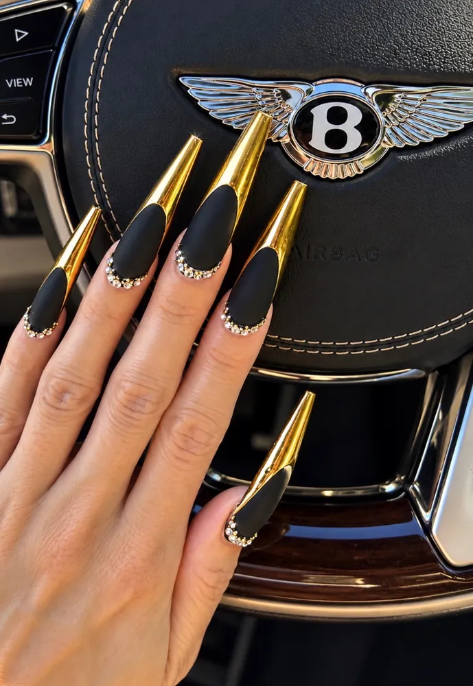 Black matte stiletto nails with gold chrome tips and a rhinestone cuticle line for New Year's Eve at NAB Nail Bar Las Vegas