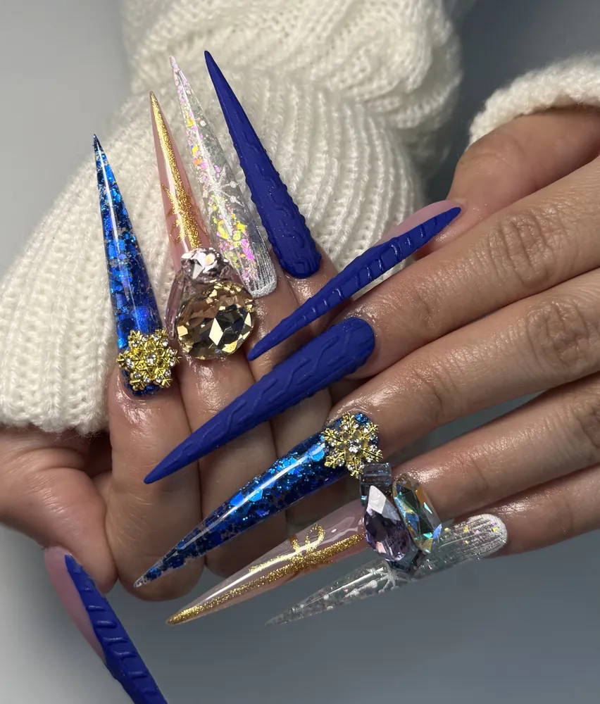 Long cobalt blue stiletto nails with cable-knit texture, blue glitter, gold snowflake charms and large crystals at NAB Nail Bar Las Vegas