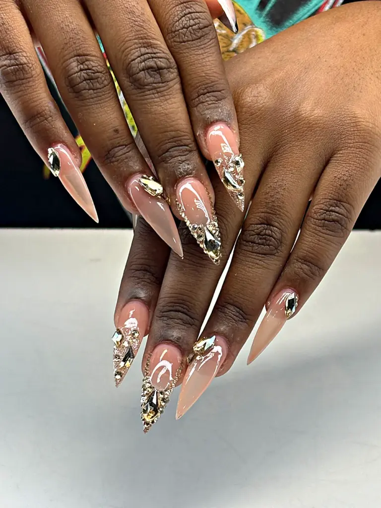 Long stiletto Gel X nails in nude with gold crystals and rhinestones at NAB Nail Bar in Las Vegas