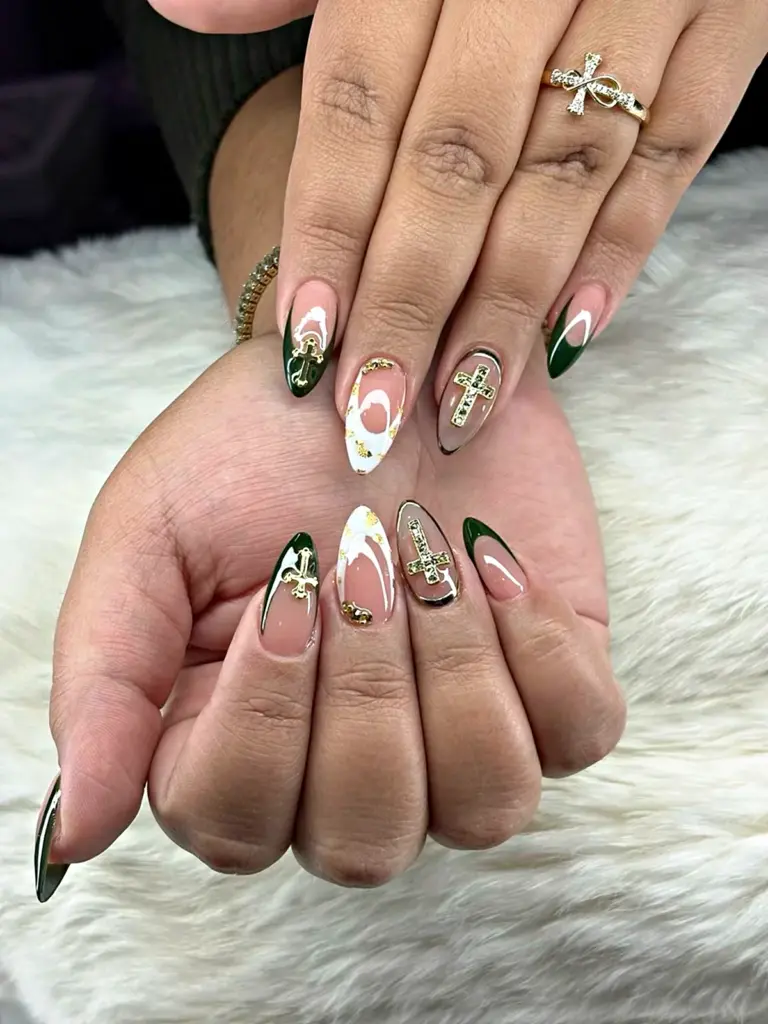 Medium almond Gel X nails with dark green French tips and gold cross charms at NAB Nail Bar in Las Vegas