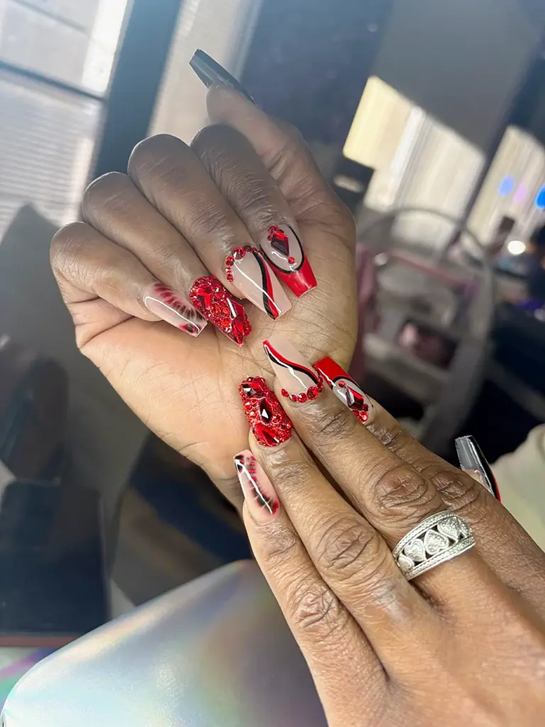 Medium coffin Gel X nails with full red rhinestone accents, red French and black swirl lines at NAB Nail Bar in Las Vegas
