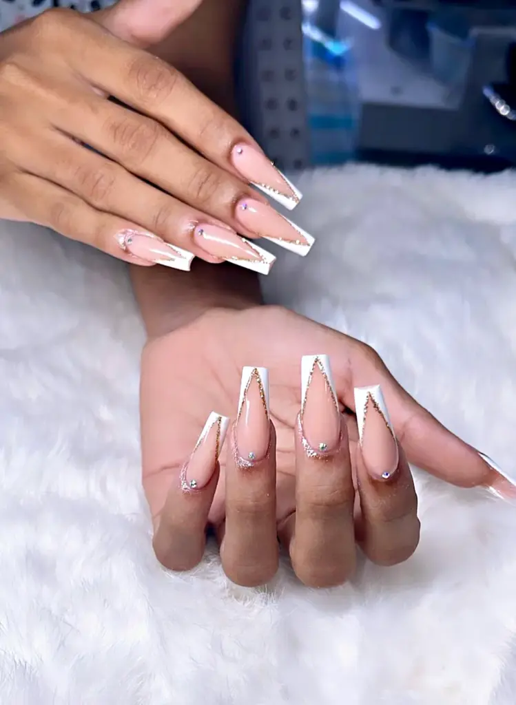 Medium coffin Gel X nails with a white V French tip, gold glitter outline and crystals at NAB Nail Bar in Las Vegas