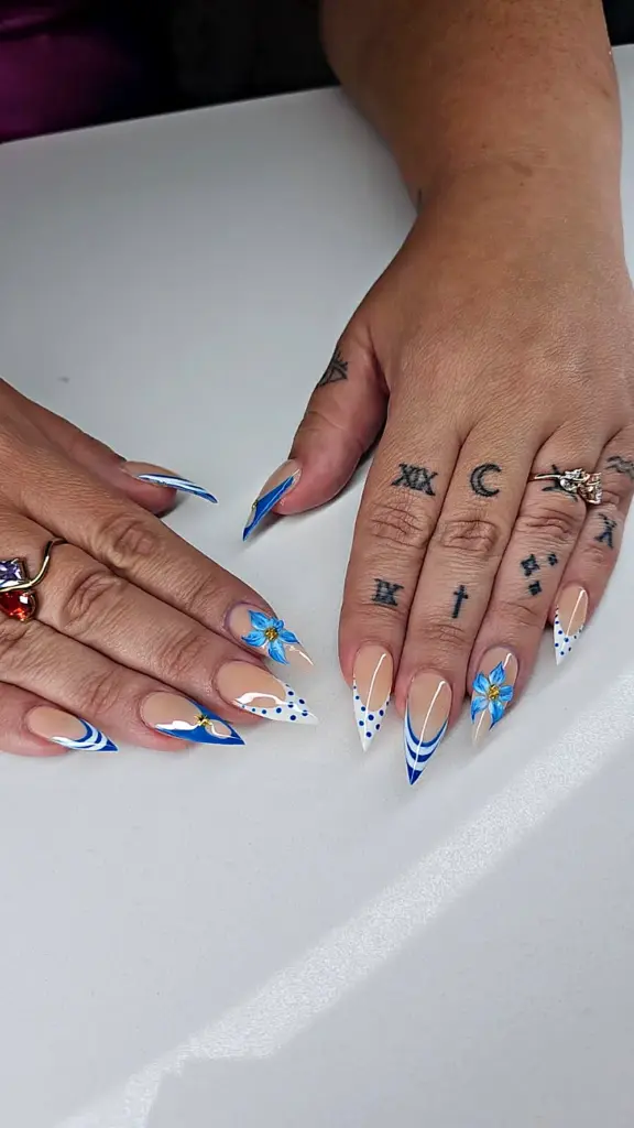 Medium stiletto Gel X nails with a blue and white French tip, polka dots and hand-painted flowers at NAB Nail Bar in Las Vegas