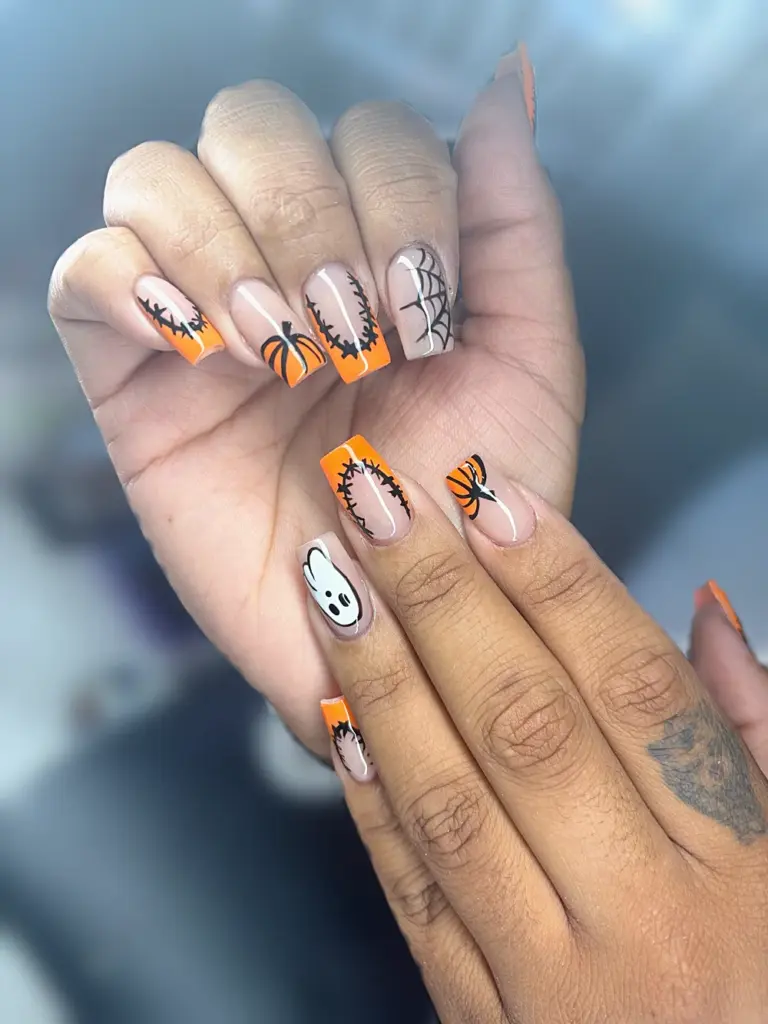 Short coffin Gel X nails with orange French tips, pumpkins, a ghost, spider webs and barbed wire at NAB Nail Bar in Las Vegas