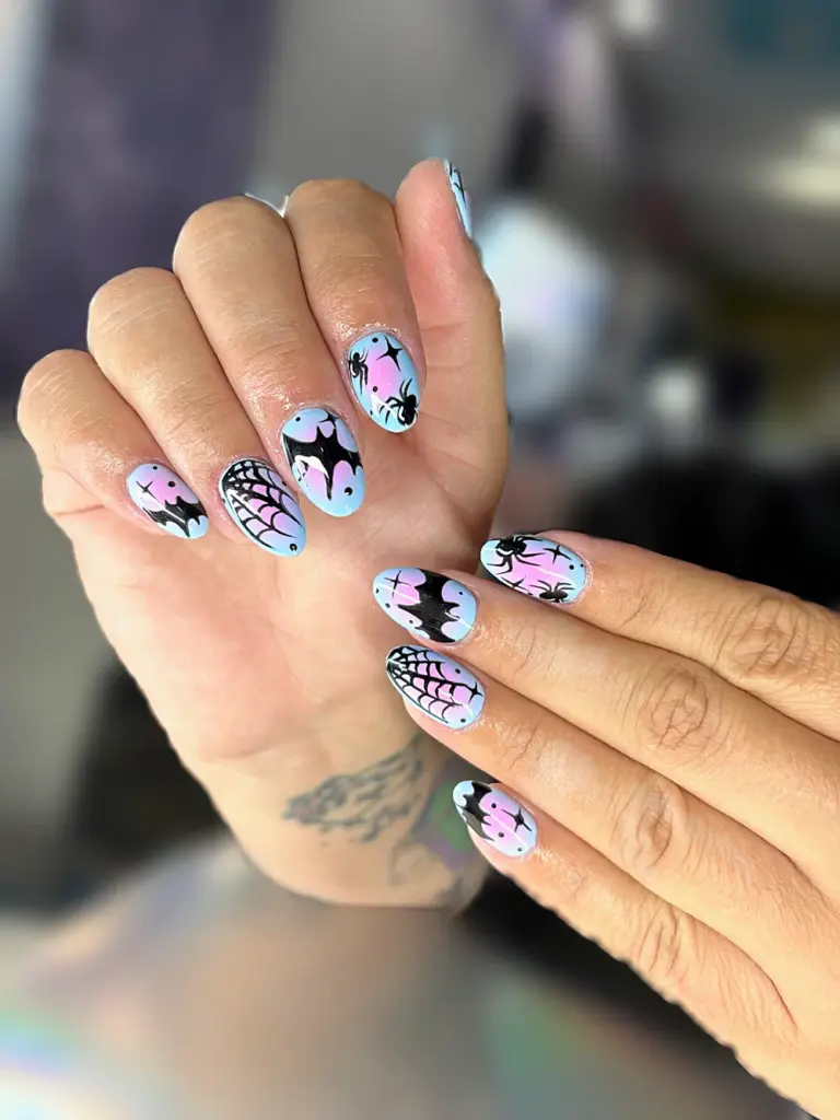 Short oval Gel X nails in pastel blue and pink ombré with hand-painted bats, spiders and webs at NAB Nail Bar in Las Vegas