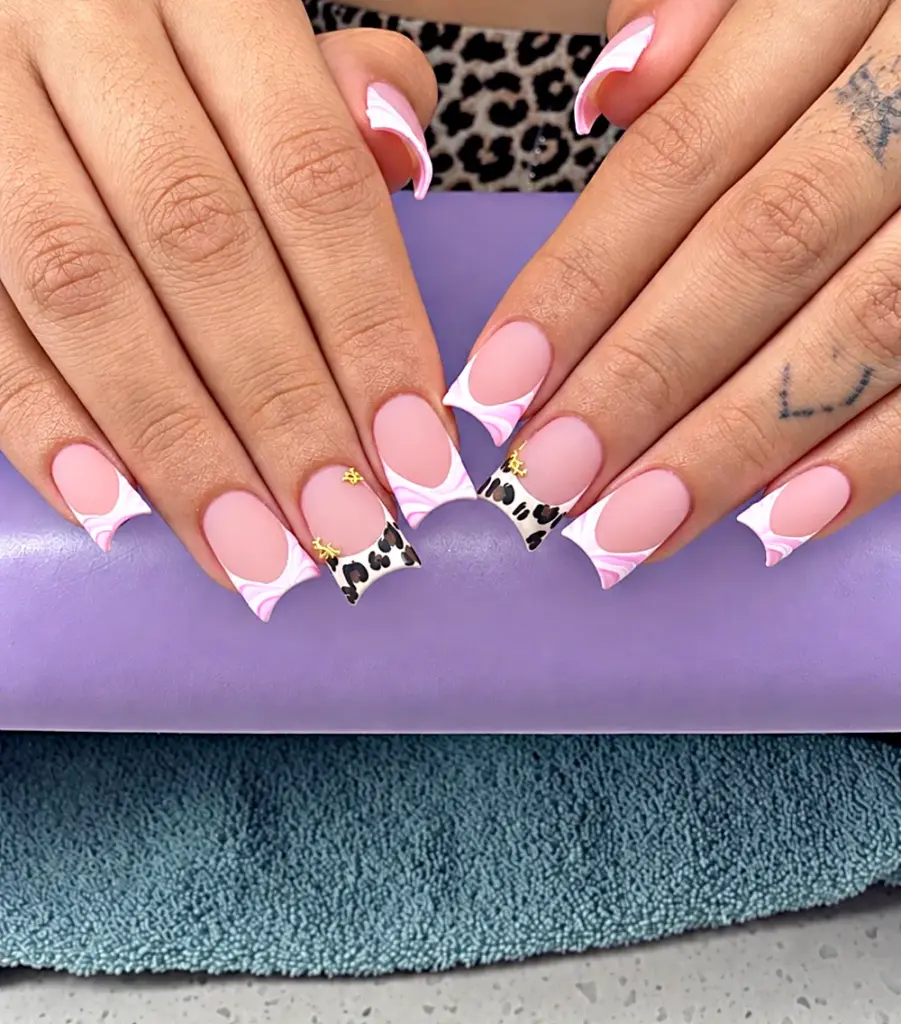 Short square Gel X nails with a pink swirl French tip, leopard accents and gold charms at NAB Nail Bar in Las Vegas