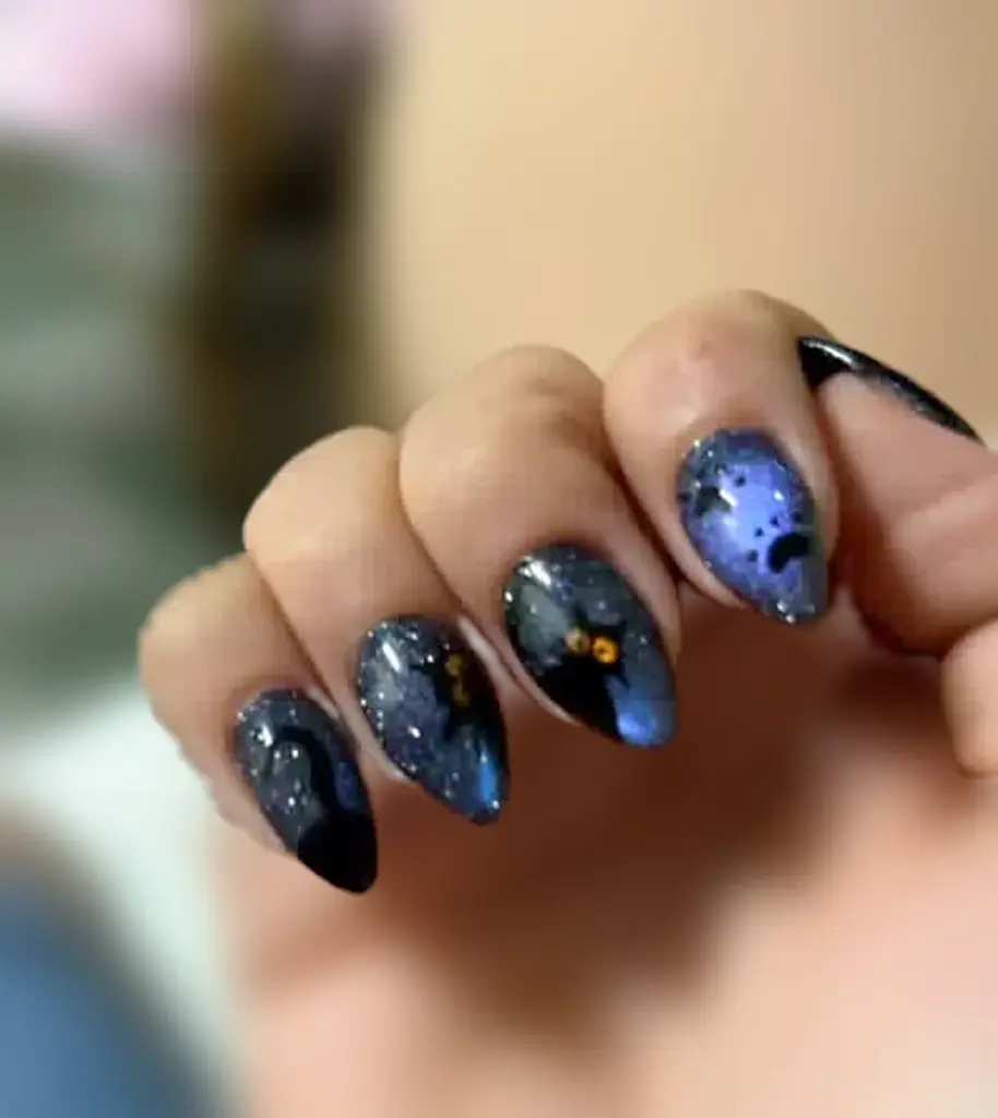 Short stiletto Gel X nails in color-changing purple and blue cat eye with hand-painted black cats at NAB Nail Bar in Las Vegas