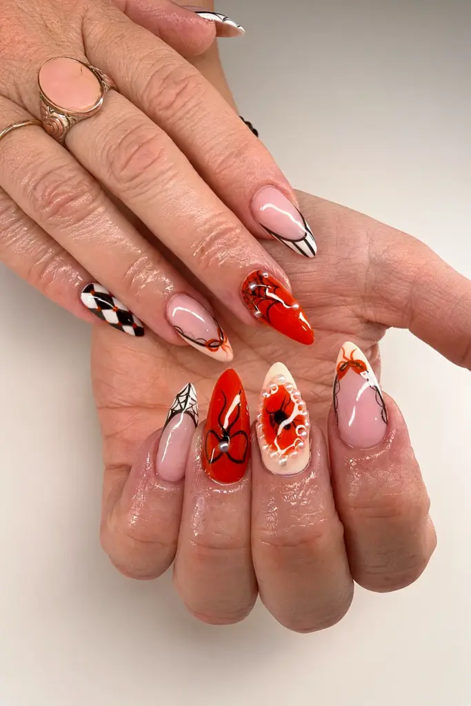 Short stiletto Gel X nails with orange jelly, hand-painted spiders, webs, harlequin and pearls at NAB Nail Bar in Las Vegas